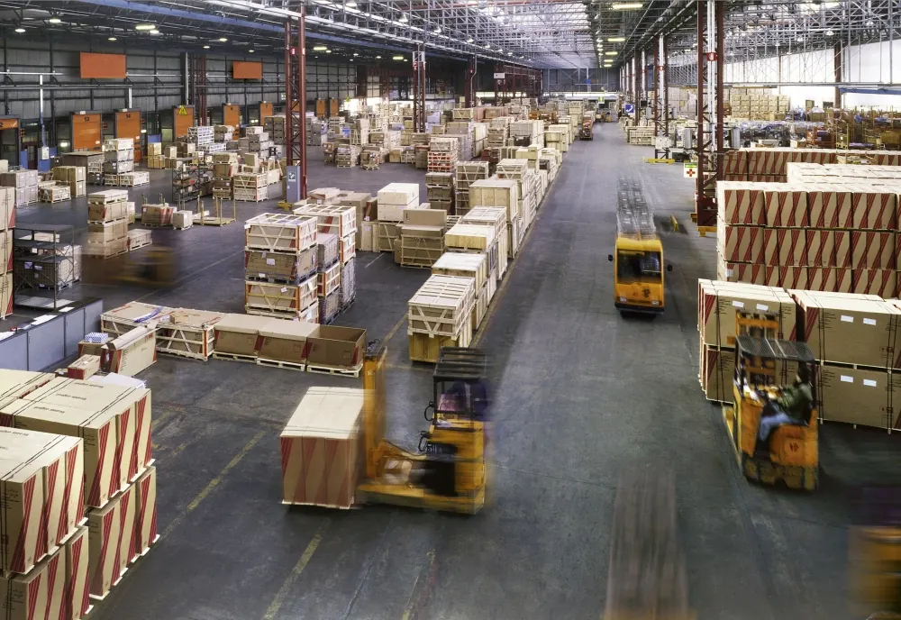 Professional movers handling heavy machinery in a warehouse for an industrial long-distance move